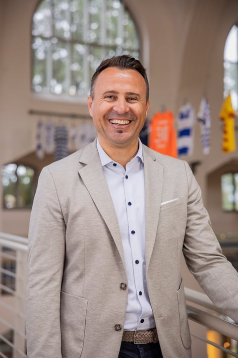 Smiling man in beige blazer and light blue shirt